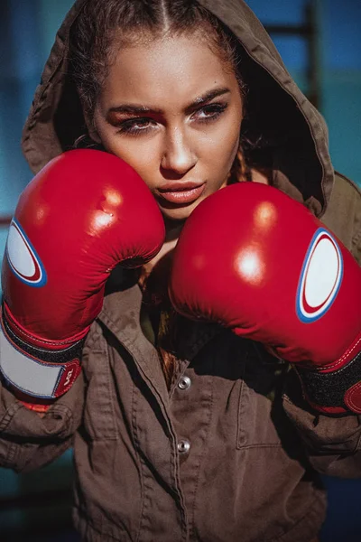 Young female boxer ready to fight in leather boxing gloves. Sexy fitness happy blonde girl in sport wear with perfect body in boxing gym posing in boxing ring. Sport, fitness, lifestyle concept