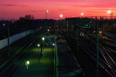 Gün batımında demiryolları. Demiryolu manzarası üzerinde alçak bulutlarda turuncu gün batımı. Sabah erkenden 