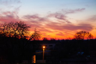 Köyün üzerinde kırmızı bulutlarla gün batımı