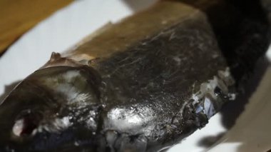 Kadının kapağı çiğ balığa yağ ekler.