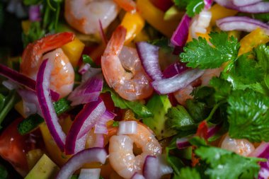 Avokado, soğan, biber, domates, maydanoz ve çam fıstıklı karides salatası.