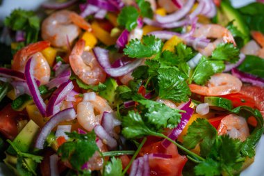 Avokado, soğan, biber, domates, maydanoz ve çam fıstıklı karides salatası.