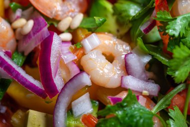 Avokado, soğan, biber, domates, maydanoz ve çam fıstıklı karides salatası.