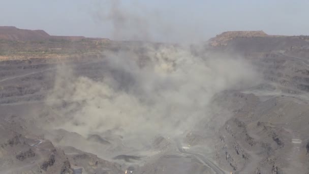 Excavatrices, camions et techniques lourdes dans la mine à ciel ouvert après explosion dans la poussière et la fumée 