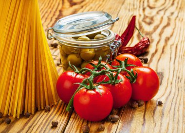 Bazı İtalyan makarna yemek pişirmek için bir kahverengi ahşap masa malzemeler: domates, makarna, zeytinyağı, biber, zeytin