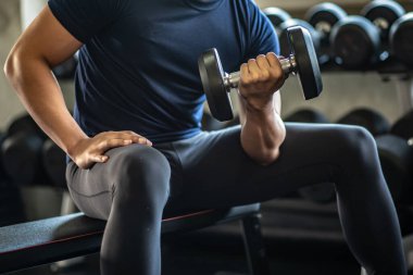 Spor salonundaki bisepslerle ağırlık kaldıran adam..