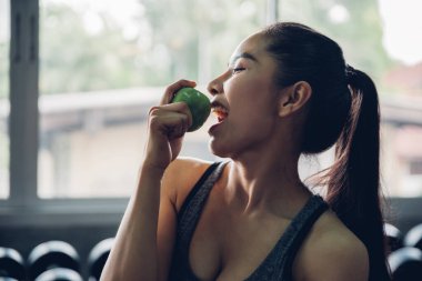 Çekici gülümseyen genç Asyalı kadın yemek için yeşil elma tutuyor.