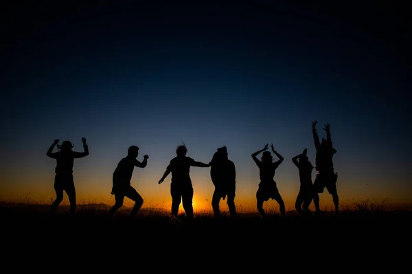 Silhuetas grupo de pessoas na montanha com pôr do sol — Fotografia de Stock