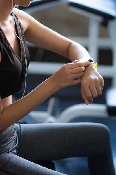 Beautiful young woman using smart watch at the gym
