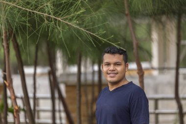 Genç Asyalı Taylandlı adamın portresi gülümsüyor ve kameraya bakıyor.