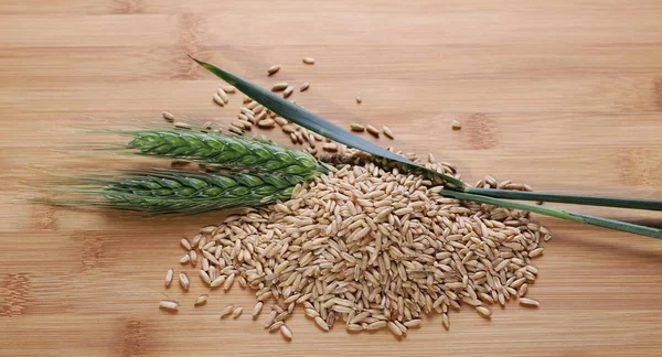 Ovesná zrna a uši pšenice na dřevěné ratan bambusový stůl — Stock fotografie