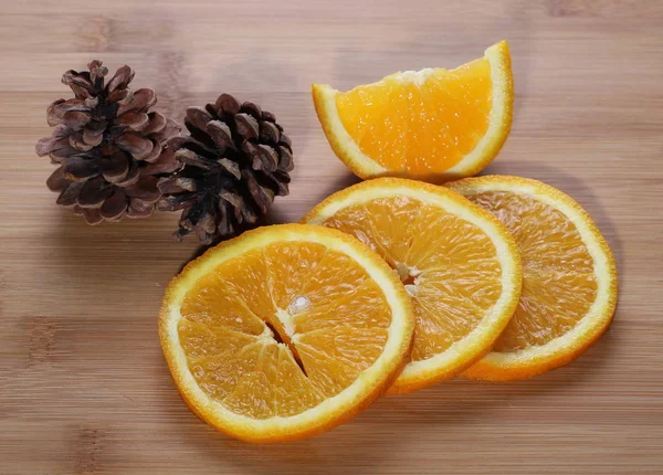Fresh oranges with slices and pine cones on a rattan bamboo table — Stock Photo, Image