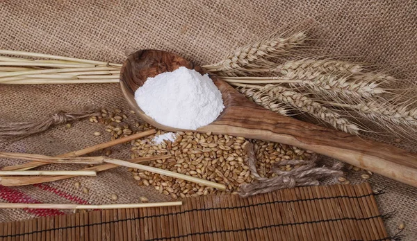 Uši pšenice, semen a mouku v vařečku na lněný pytel — Stock fotografie