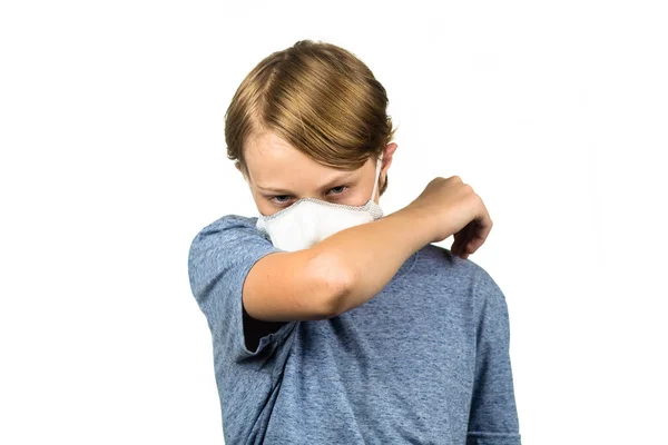 10代の少年は肘にマスクをつけて咳をした 白に隔離された ストック写真