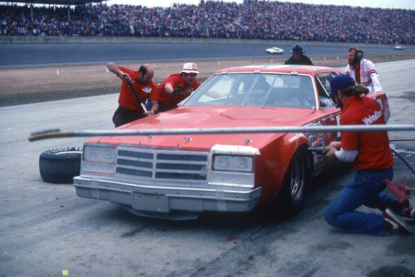 1974 Pit Crew working on race car during a race.