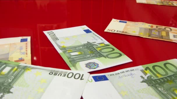 Billetes en euros que aparecen en una superficie de cristal rojo — Vídeo de stock