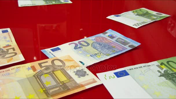 Euro banknotes appearing on a red glass surface — Stock Video