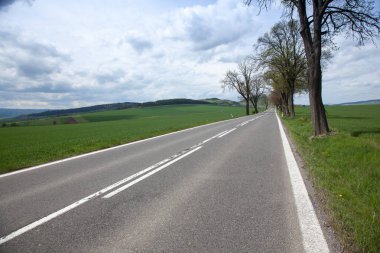 asfalt yol yeşil alan ve bulutların üstünde mavi gökyüzü ile