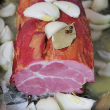 Çiğ domuz rostosu, soğanlı kassler rostosu, körfez yapraklı, kavrulmaya hazır baharatlar.