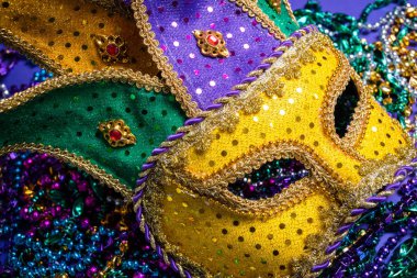 Colorful Mardi Gras or carnival mask on a purple background with beads.