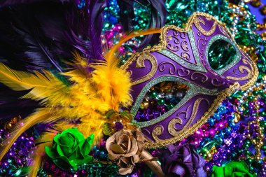 Colorful Mardi Gras or carnival mask on a purple background with beads.