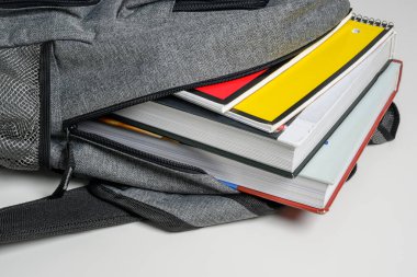 School backpack on a white background with books and spiral notebooks