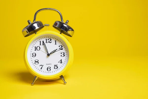 A yellow alarm clock on a yellow background — 图库照片