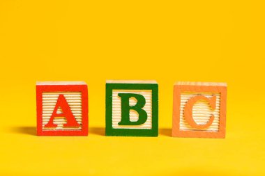 Wooden ABC blocks on yellow background