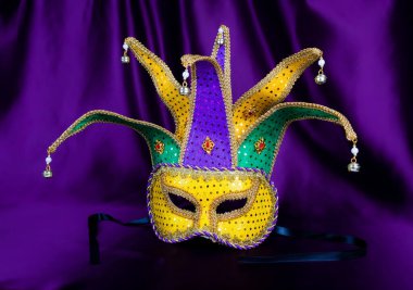 Colorful Mardi Gras mask on purple background with beads