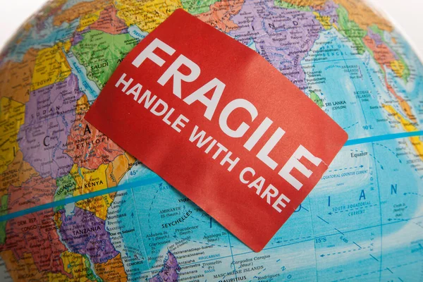 An Earth globe with a fragile hand with care sticker