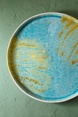 Üst açı mavi turkuaz kaplama ve yeşil desenli masaya karşı çay eşleşmesi.