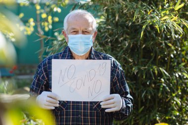 Ellerinde maske ve eldiven tutan yaşlı adamın elleri..