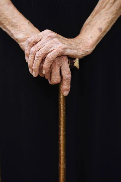 Olgun kadınların elleri katlanır ve siyah arka plana yaslanır. Elleri buruşuk büyükanne. Yaş 92.