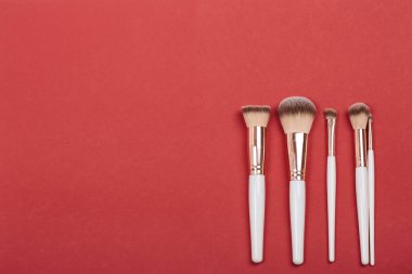 Kozmetik fırçalar sette kırmızı sulu arka planda, üst görüntüde. Makyaj sanatçısının işi..