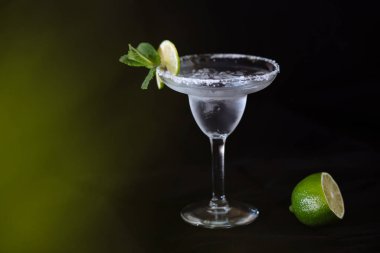 Siyah arka plandaki gece kulübü restoranında limonlu ve naneli hafif alkollü kokteyl için klasik cam. Modern alkollü içecek.