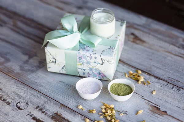Anti aging natural cosmetic face mask based on algae and matcha tea is on gift box on white wooden table. Natural cosmetic for daily face care.