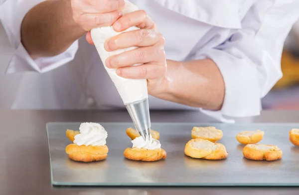 Cocinero pastelero con profiteroles — Foto de Stock