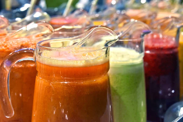 Pitchers with different sorts of fresh vegetable and fruit juice — Stock Photo, Image