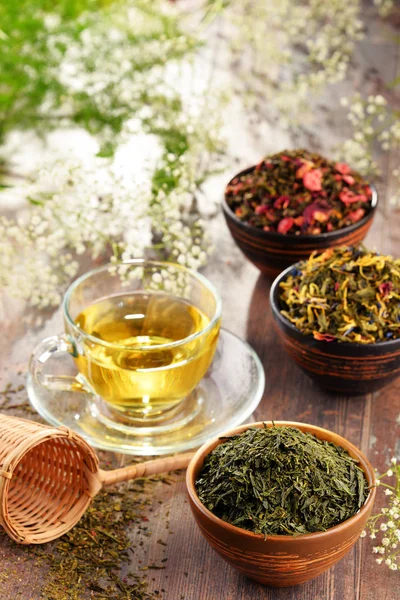 Samenstelling met kop van thee en kommen van thee bladeren — Stockfoto