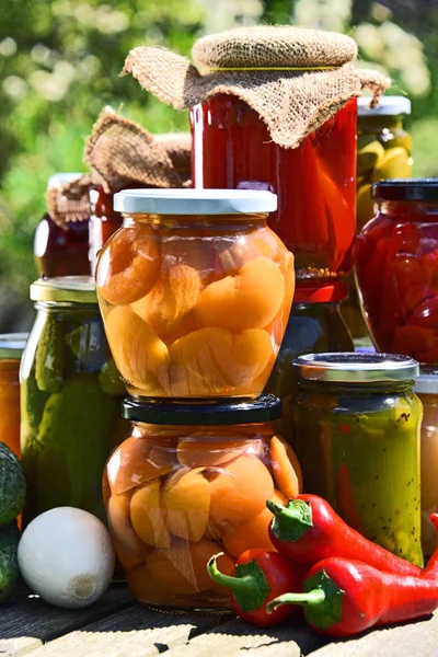 Gläser mit eingelegtem Gemüse und Obst im Garten — Stockfoto