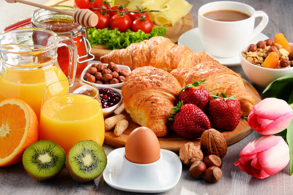 Breakfast consisting of croissants, coffee, fruits, orange juice
