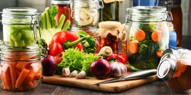 Kavanoz ile marine edilmiş yiyecek ve çiğ sebze kesme tahtası üzerinde