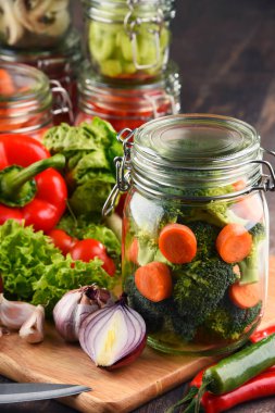 Kavanoz ile marine edilmiş yiyecek ve çiğ sebze kesme tahtası üzerinde