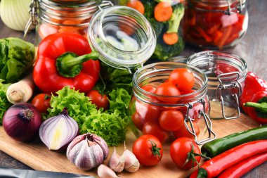 Kavanoz ile marine edilmiş yiyecek ve çiğ sebze kesme tahtası üzerinde