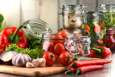 Kavanoz ile marine edilmiş yiyecek ve çiğ sebze kesme tahtası üzerinde