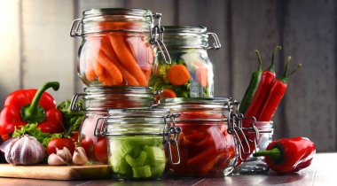 Kavanoz ile marine edilmiş yiyecek ve çiğ sebze kesme tahtası üzerinde