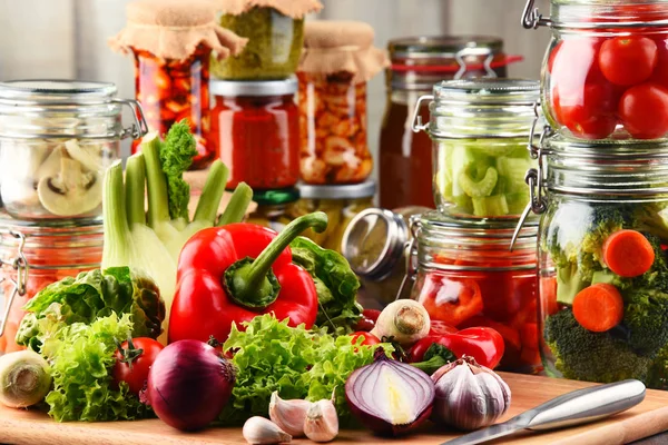 Słoiki z jedzeniem marynowane i surowe warzywa na deska do krojenia — Zdjęcie stockowe