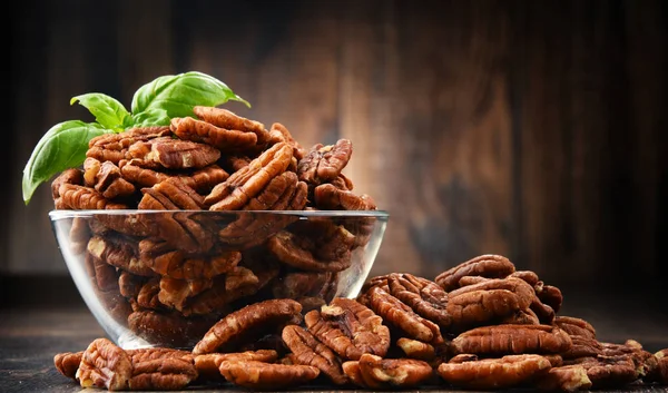 Mísa s pekanovými ořechy na dřevěný stůl. — Stock fotografie