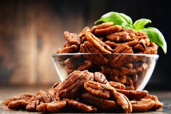 Schüssel mit Pekannüssen auf Holztisch. — Stockfoto