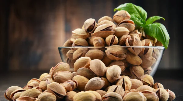 Schüssel mit Pistazien auf Holztisch — Stockfoto